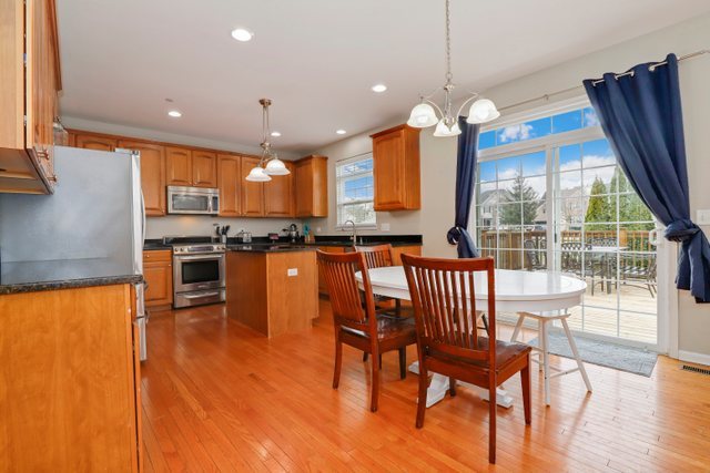 5961 Chatham Drive Hoffman Estates, IL 60192 - Photo 14 of 39 a open kitchen with stainless steel appliances granite countertop a stove top oven a dining table and chairs with wooden floor
