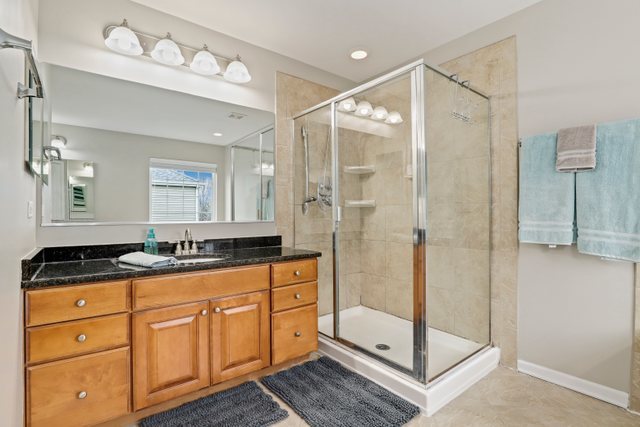 5961 Chatham Drive Hoffman Estates, IL 60192 - Photo 23 of 39 a bathroom with a granite countertop sink a mirror a shower and a bathtub