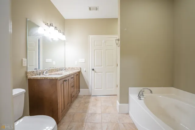 a bathroom with a granite countertop sink a toilet and bathtub