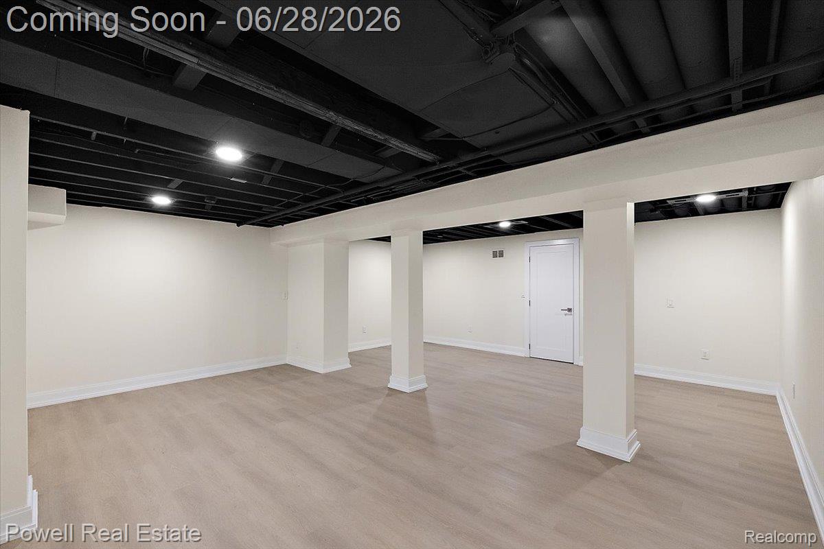 1447 Ravineview Court, Unit C12 Bloomfield Hills, MI 48304 - Photo 48 of 49 Finished lower level featuring light wood-finish flooring, recessed lighting, white trim, a white interior door, and exposed black ceiling joists