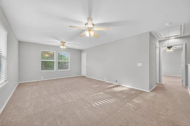 an empty room with windows and fan chandelier