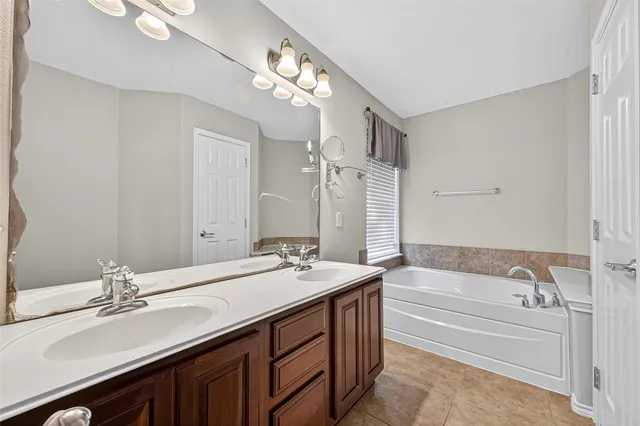 a spacious bathroom with a tub sink and mirror