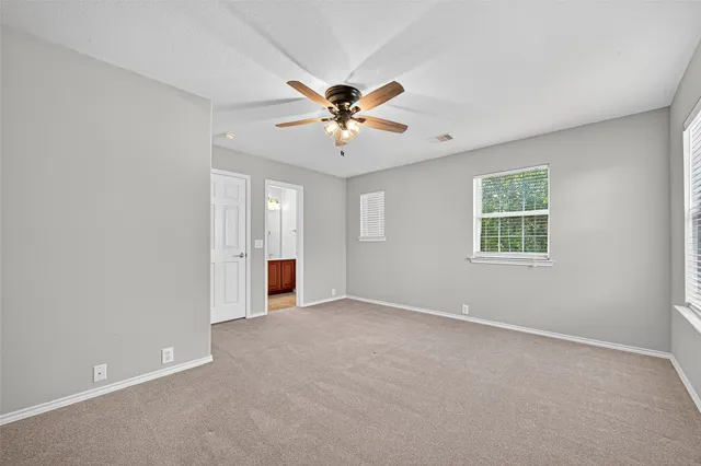an empty room with fan and windows