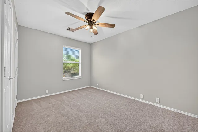 an empty room with windows and fan