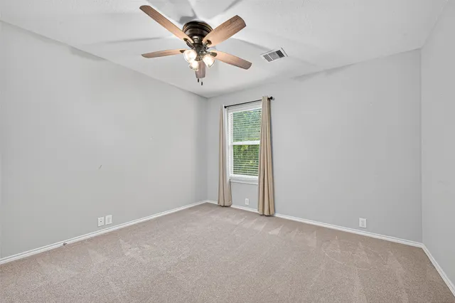 an empty room with a window and a fan