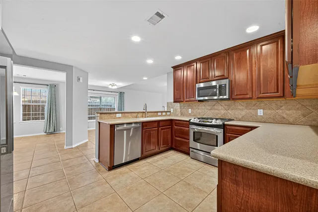 a kitchen with stainless steel appliances granite countertop a stove refrigerator sink and microwave