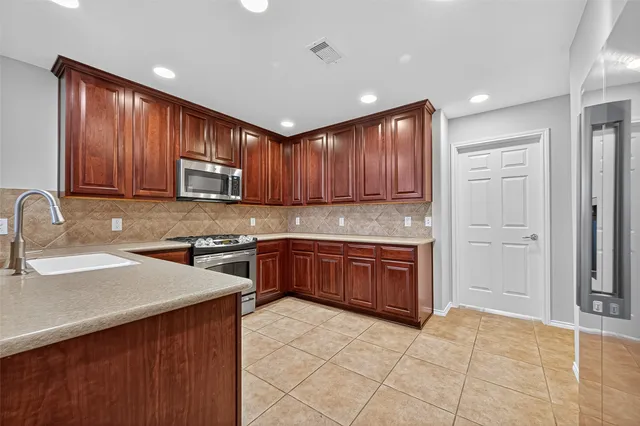 a kitchen with stainless steel appliances granite countertop wooden cabinets a stove top oven a sink and dishwasher