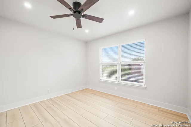 an empty room with a window and a ceiling fan