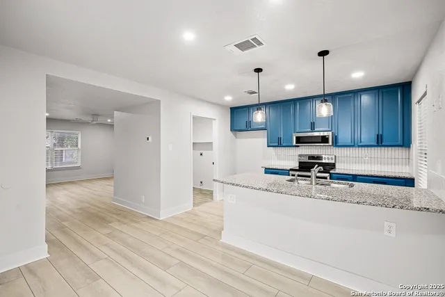 a kitchen with stainless steel appliances granite countertop a sink refrigerator and cabinets