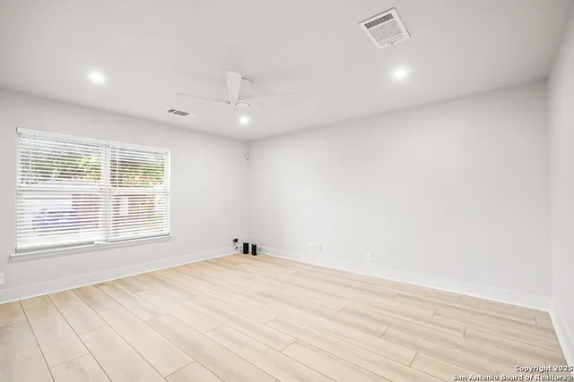 an empty room with wooden floor and windows