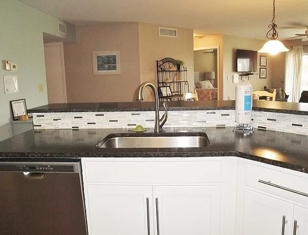 a kitchen with kitchen island granite countertop a sink and a stove top oven