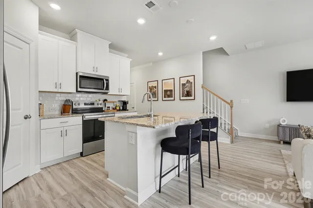 a kitchen with stainless steel appliances kitchen island granite countertop a stove a sink a microwave a dining table and chairs