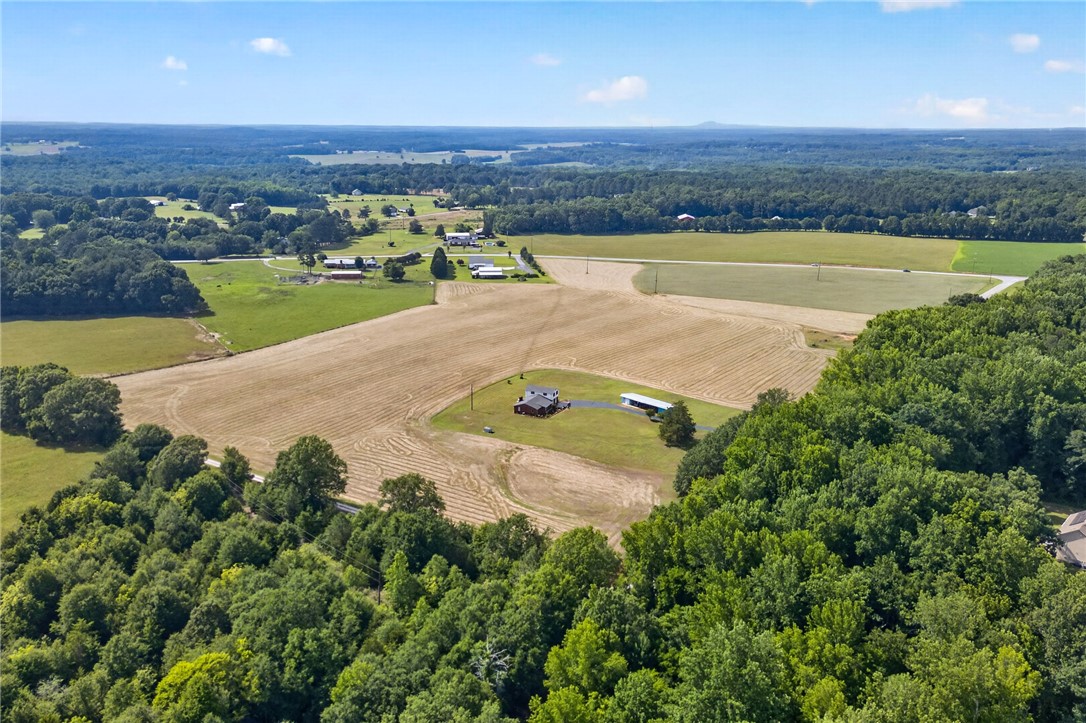 145 State Rd S-4-935 Pendleton, SC 29670 - Photo 32 of 47 Breathtaking aerial views showcase a rural residential property nestled amidst lush woodlands and expansive fields.