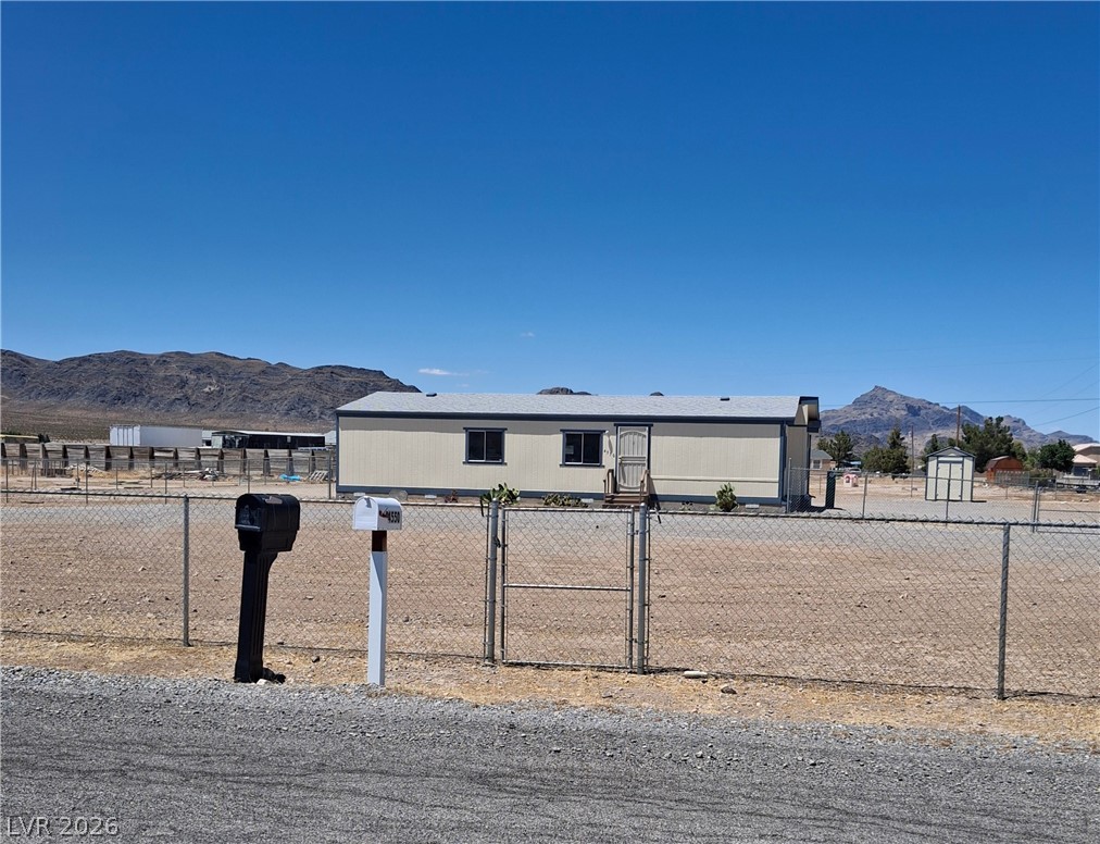 4550 Horn Road Pahrump, NV 89048 - Photo 2 of 12 A manufactured residence with mountain views, offering privacy behind a chain-link fence.