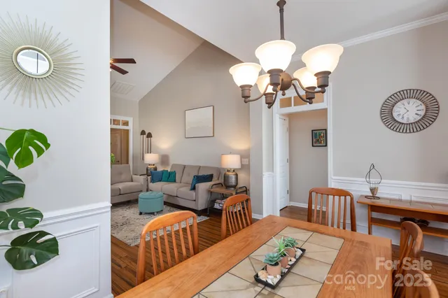 a living room with dining table and a chandelier