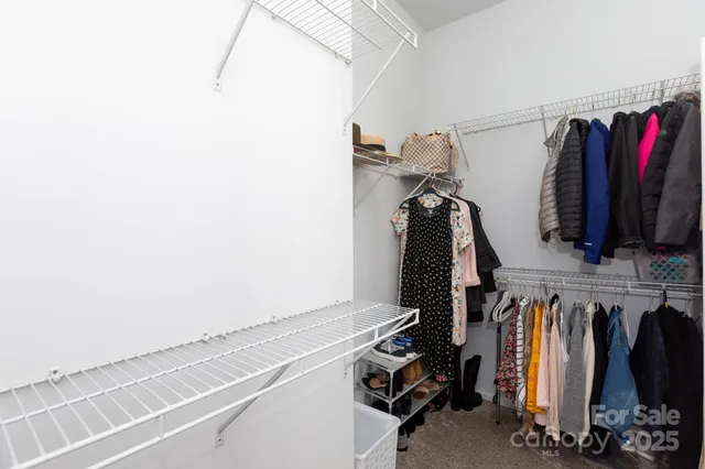 a view of walk in closet with clothes and shoes