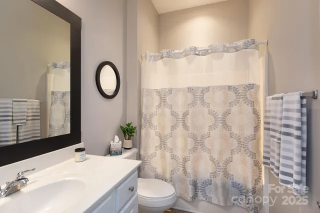 a bathroom with a granite countertop bathtub sink vanity mirror and toilet