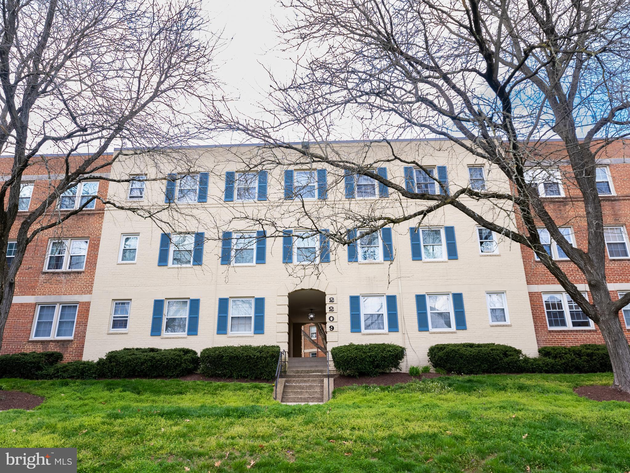 a front view of a house with garden and trees