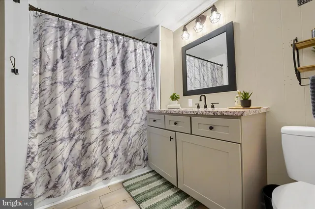 a bathroom with a granite countertop sink vanity mirror and a shower
