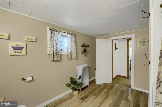 a view of a hallway with wooden floor and a bathroom