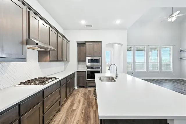 a large white kitchen with stainless steel appliances granite countertop a stove and a sink