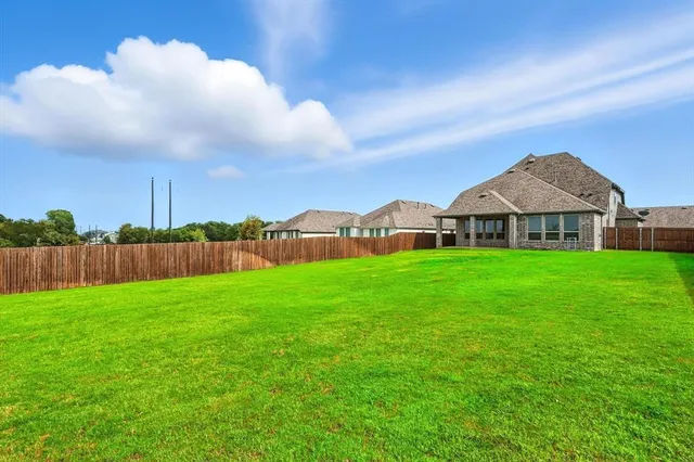 a view of a big house with a big yard and large trees