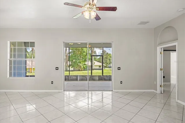 a view of an empty room with window and chandelier fan
