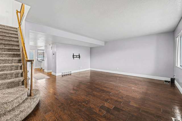 34 Benchmark Village Tooele, UT 84074 - Photo 4 of 35 Unfurnished living room featuring dark wood-style floors and plenty of natural light