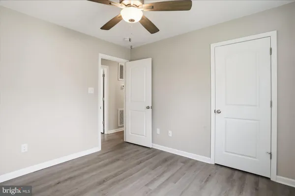 an empty room with wooden floor fan and windows