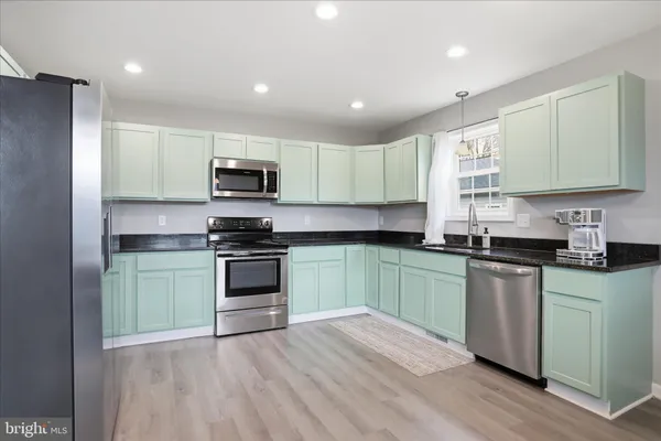 a kitchen with granite countertop a stove top oven a sink dishwasher and a refrigerator with wooden floor