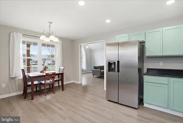 a kitchen with stainless steel appliances granite countertop a refrigerator a stove a dining table and chairs with wooden floor