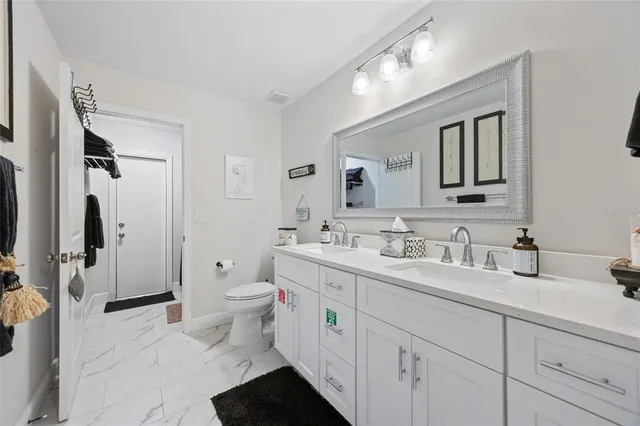 a spacious bathroom with a toilet sink double vanity and mirror