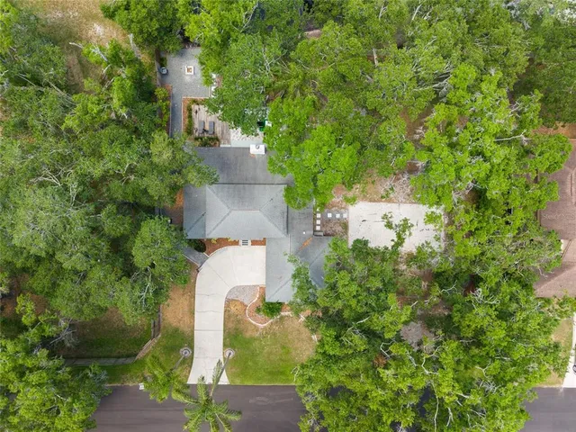 an aerial view of residential house with outdoor space and trees all around
