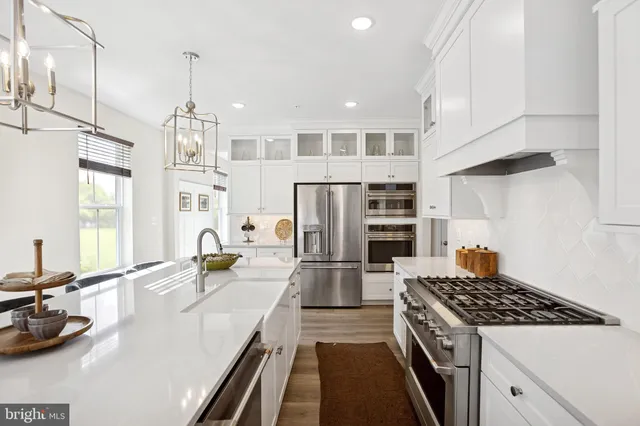 a kitchen with refrigerator a stove and a sink with wooden floor