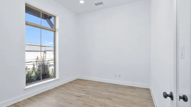 a view of an empty room with wooden floor and a window