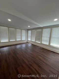 a view of an empty room with wooden floor and window
