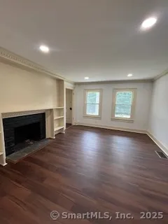an empty room with wooden floor fireplace and windows