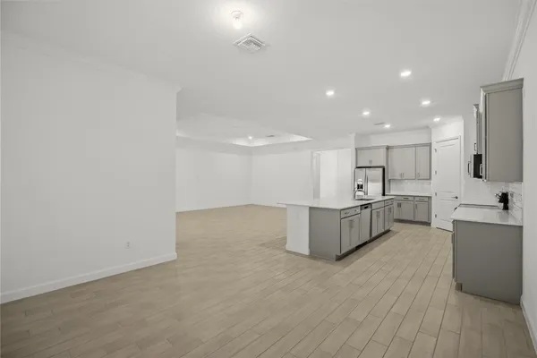 a large room with kitchen island a sink wooden floor and white cabinets