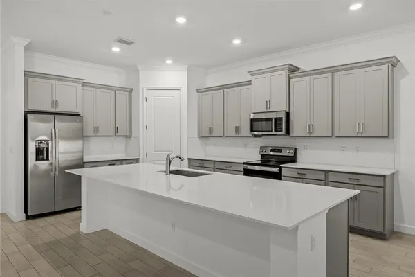 a kitchen with stainless steel appliances a sink a stove a microwave a sink a refrigerator and cabinets