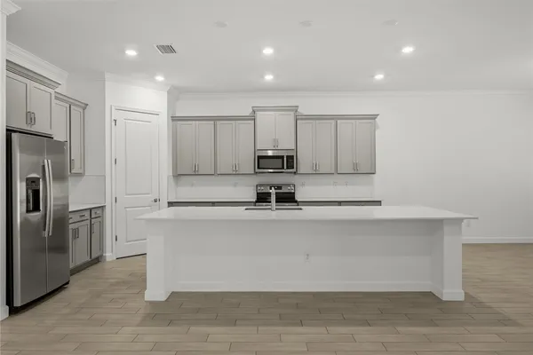 a view of a kitchen with kitchen island a sink wooden floor and stainless steel appliances