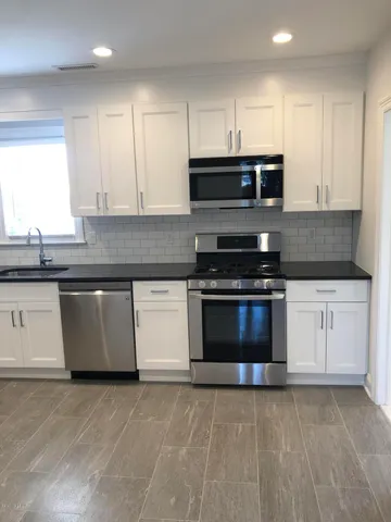 a kitchen with granite countertop a stove top oven sink and cabinets