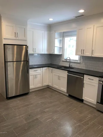 a kitchen with a sink a stove a refrigerator and white cabinets