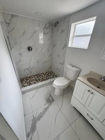 a bathroom with a granite countertop sink a toilet and a shower