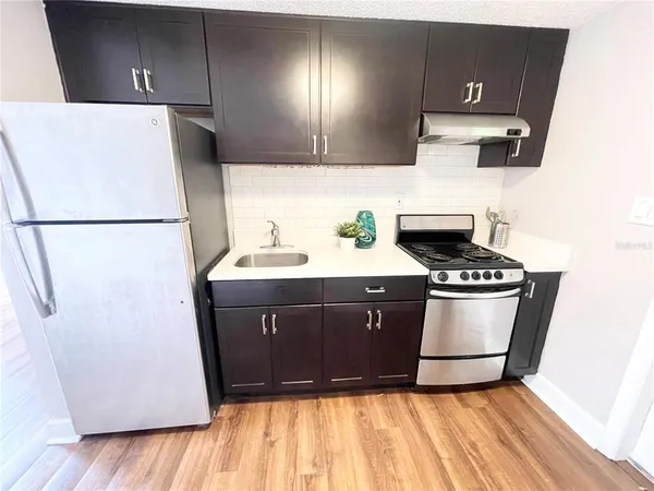 a kitchen with a refrigerator a stove and wooden floor