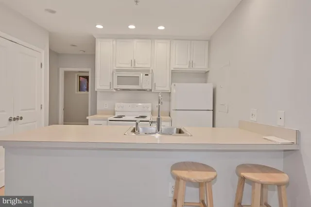 a kitchen with stainless steel appliances granite countertop a sink a stove a refrigerator and white cabinets with wooden floor