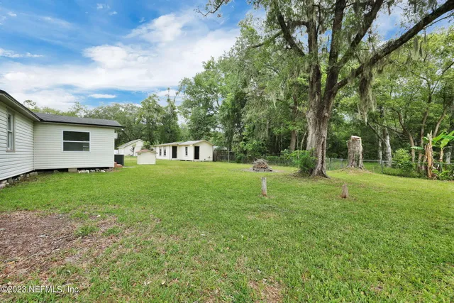 a view of a house with backyard and a tree