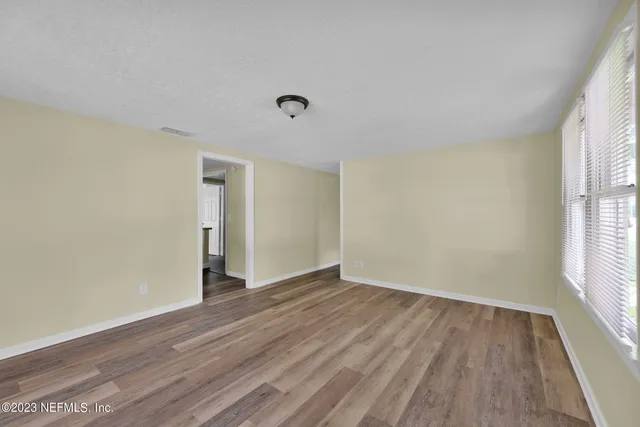 a view of an empty room with wooden floor and a window
