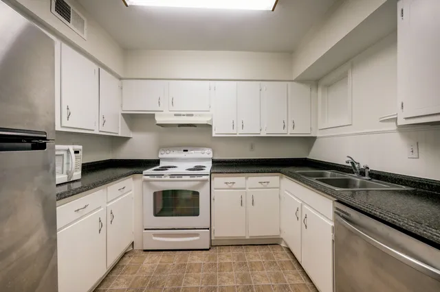 a kitchen with granite countertop white cabinets and white appliances