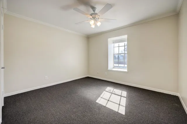 an empty room with windows and ceiling fan