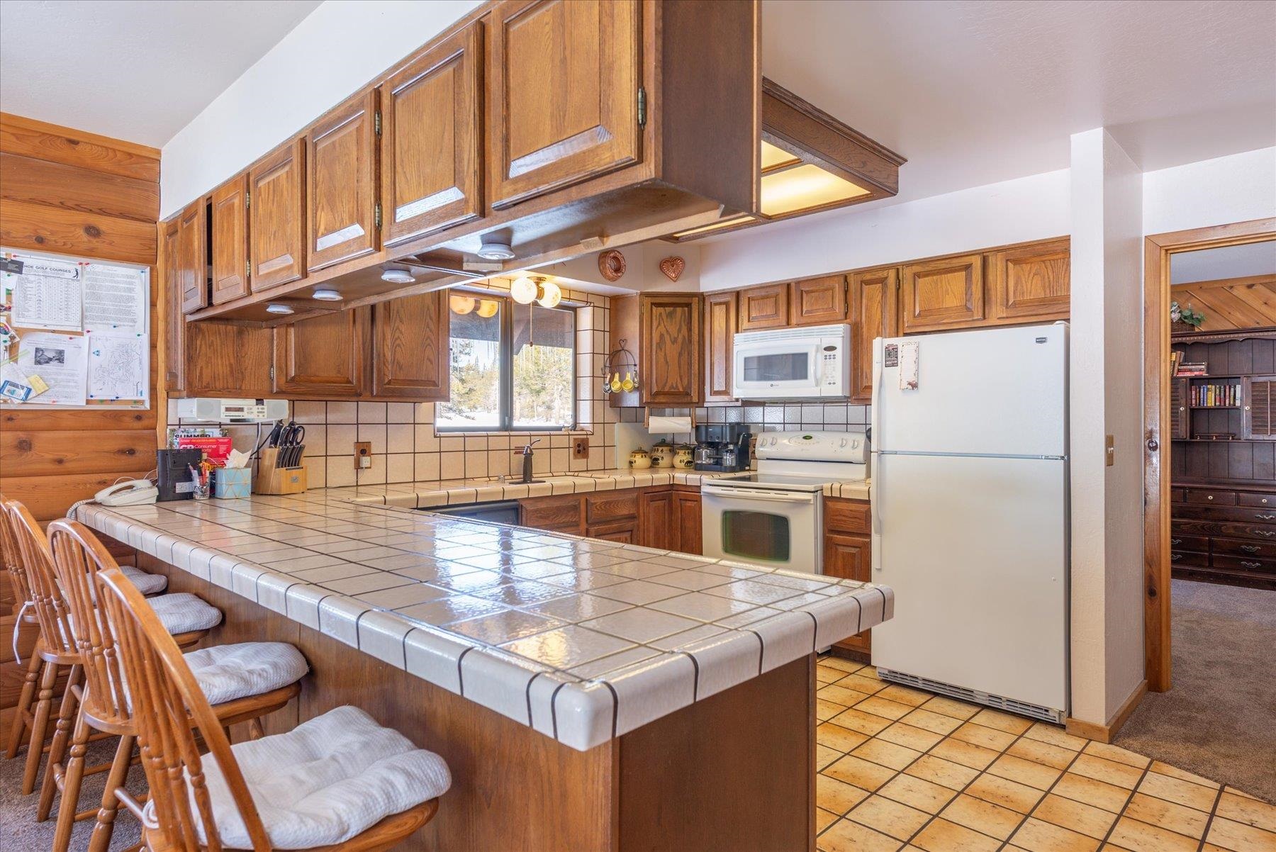 17080 Ski Slope Way Truckee, CA 96161 - Photo 5 of 22 a kitchen with stainless steel appliances granite countertop a table chairs in it and a refrigerator